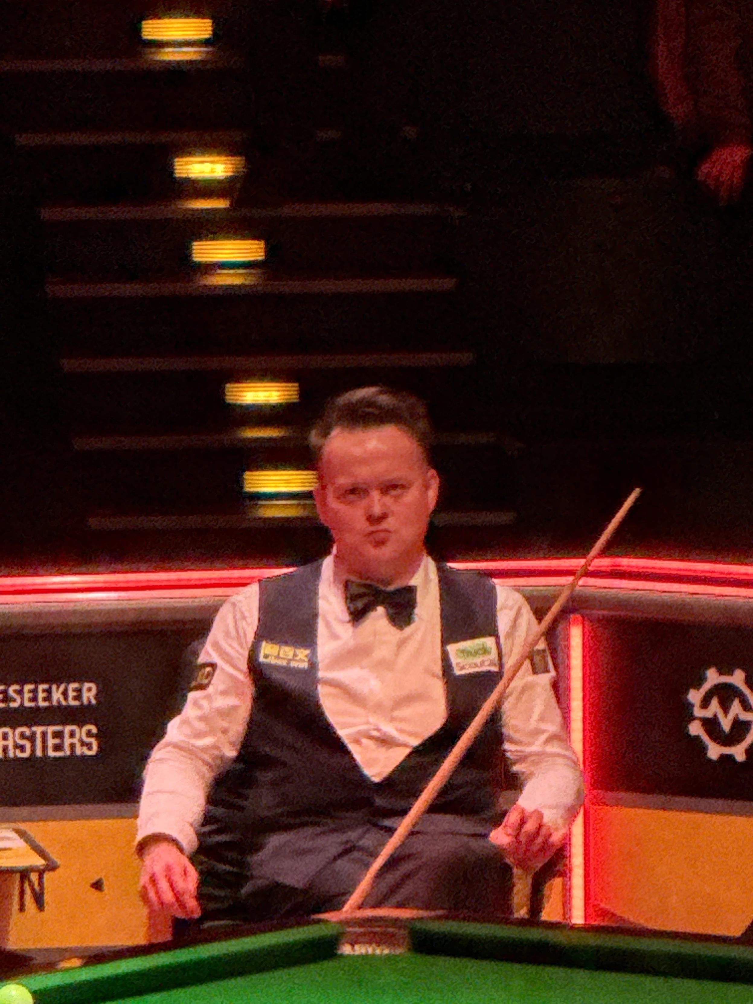 Shaun Murphy siedzący w fotelu w przerwie między partiami, oświetlenie areny sprawiło, że wygląda na bardzo czerwonego
