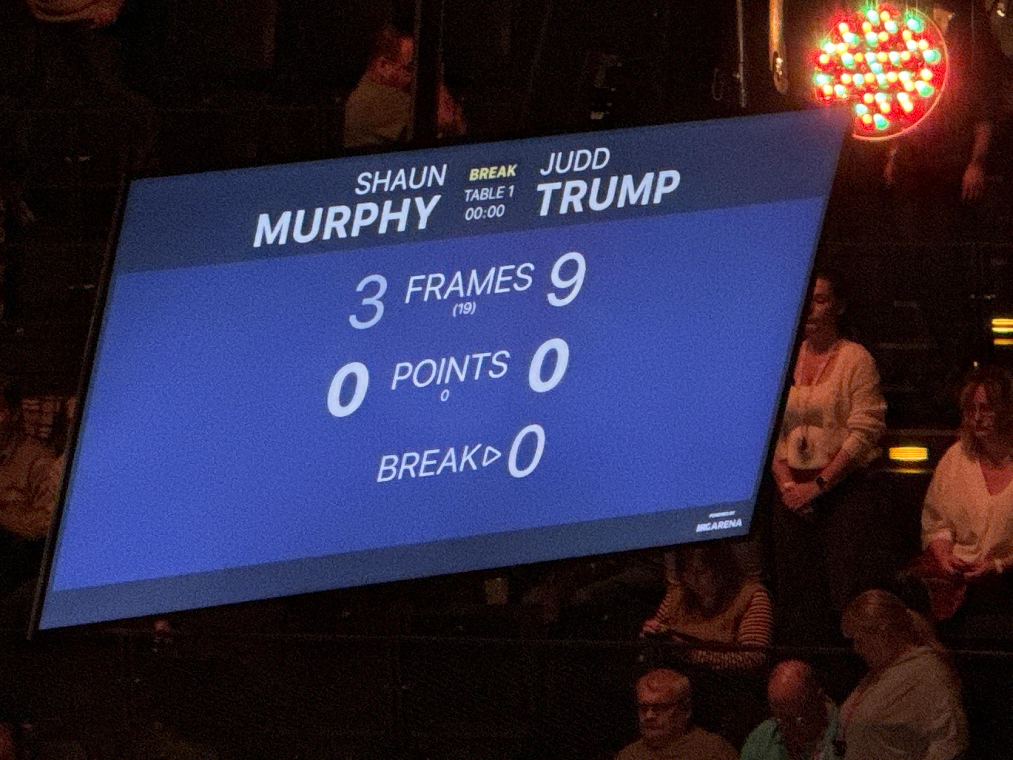Zdjęcie ekranu wyświetlającego wynik finałowego meczu turnieju snookerowego German Masters. Shaun Murphy kontra Judd Trump, wynik w trakcie ostatniej przerwy: 3 do 9. Gra toczy się do 10 wygranych frame’ów.