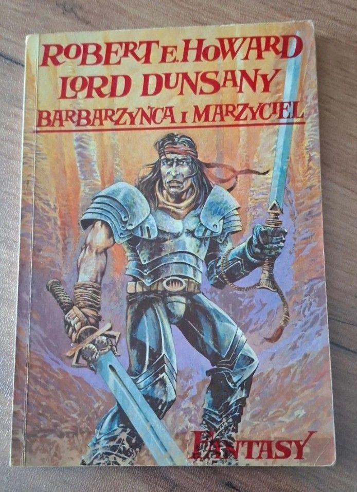 Okładka książki "Lord Dunsany. Barbarzyńca i marzyciel". Przedstawia prawdopodobnie głównego bohatera, z wielkim mieczem w każdej ręce, napierśniku od zbroi płytowej, spodniach przypominających dżinsy (?) i bandanie na głowie. Wszystko tu jest źle narysowane, kolory są nieudolnie położone, twarz bohatera przypomina trupa. Nie umiem tego w pełni opisać.