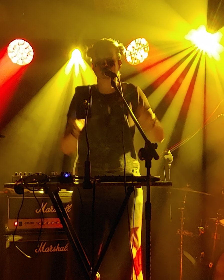 wokalistka na scenie, dziwny makijaż, w tle żółte światło