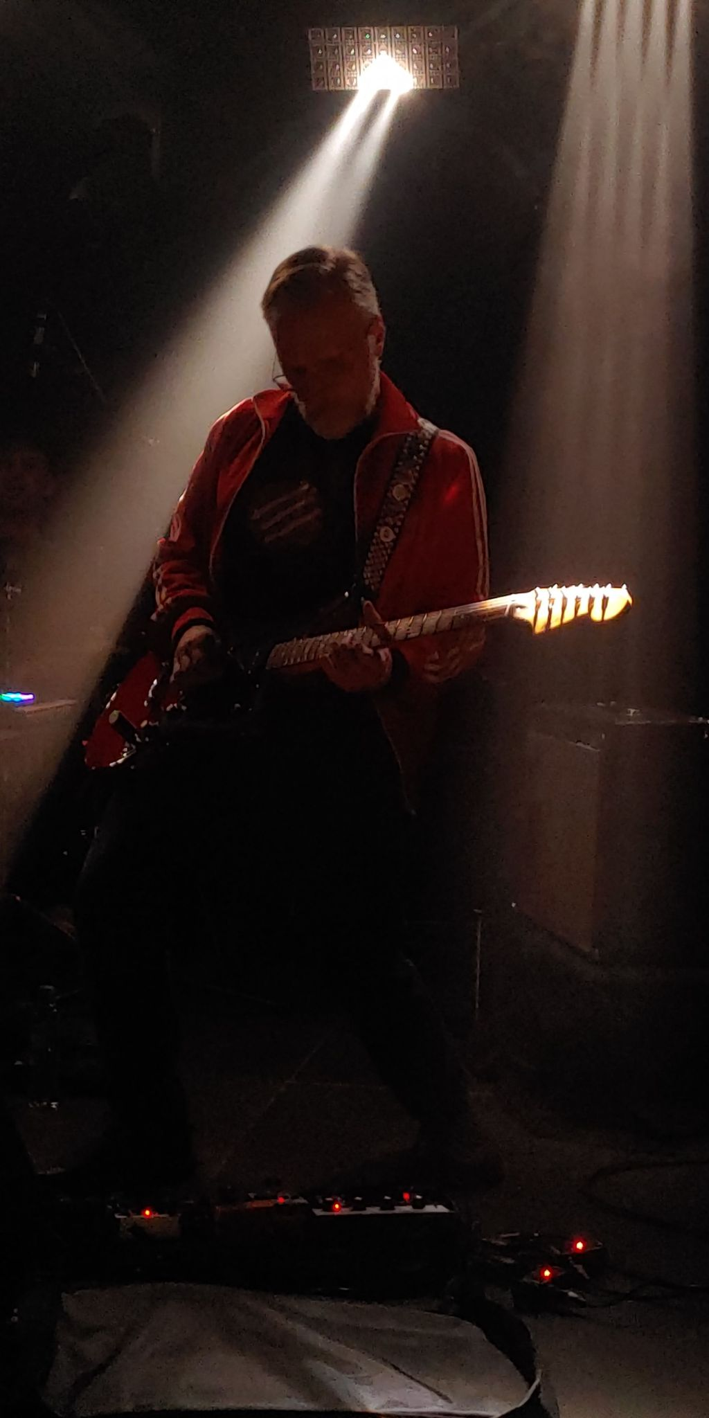 gitarzysta na scenie, czerwona bluza adidas, gitara fender