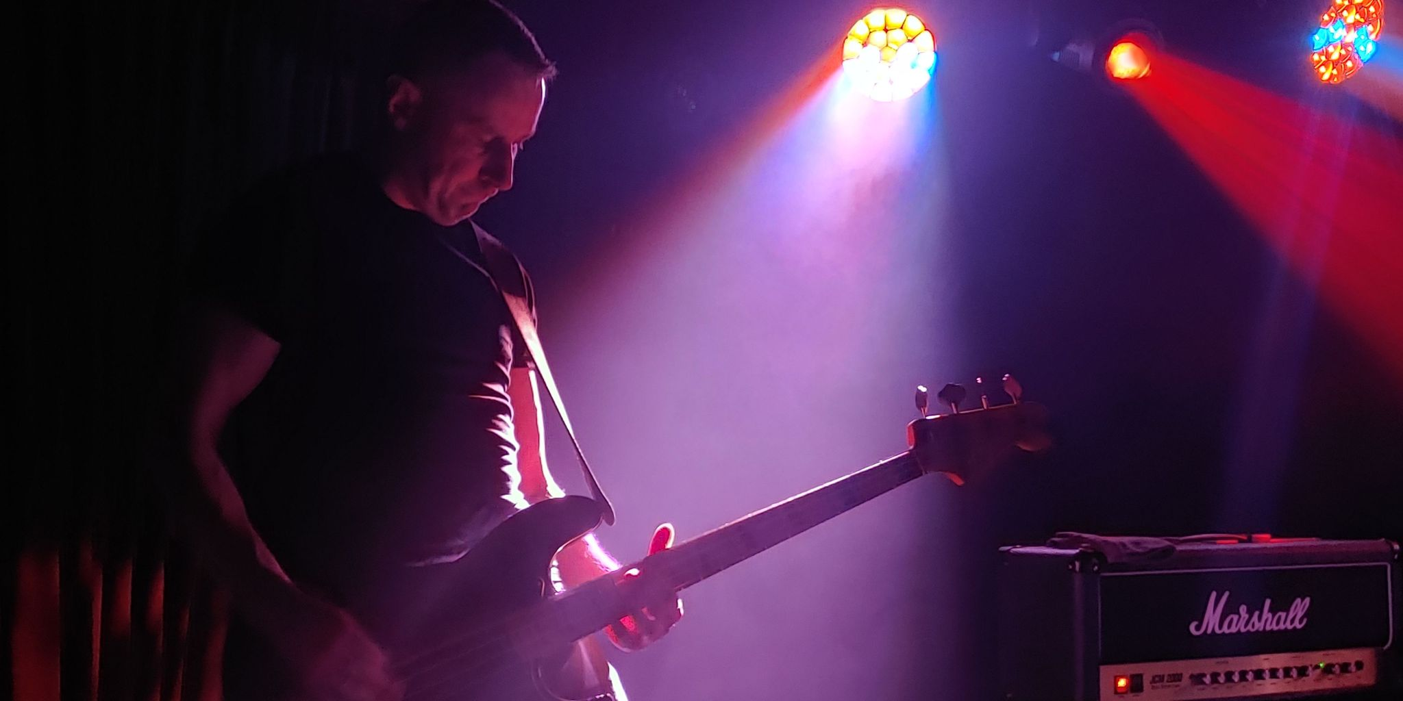 basista na scenie, fioletowo-żółte światło, gitara fender