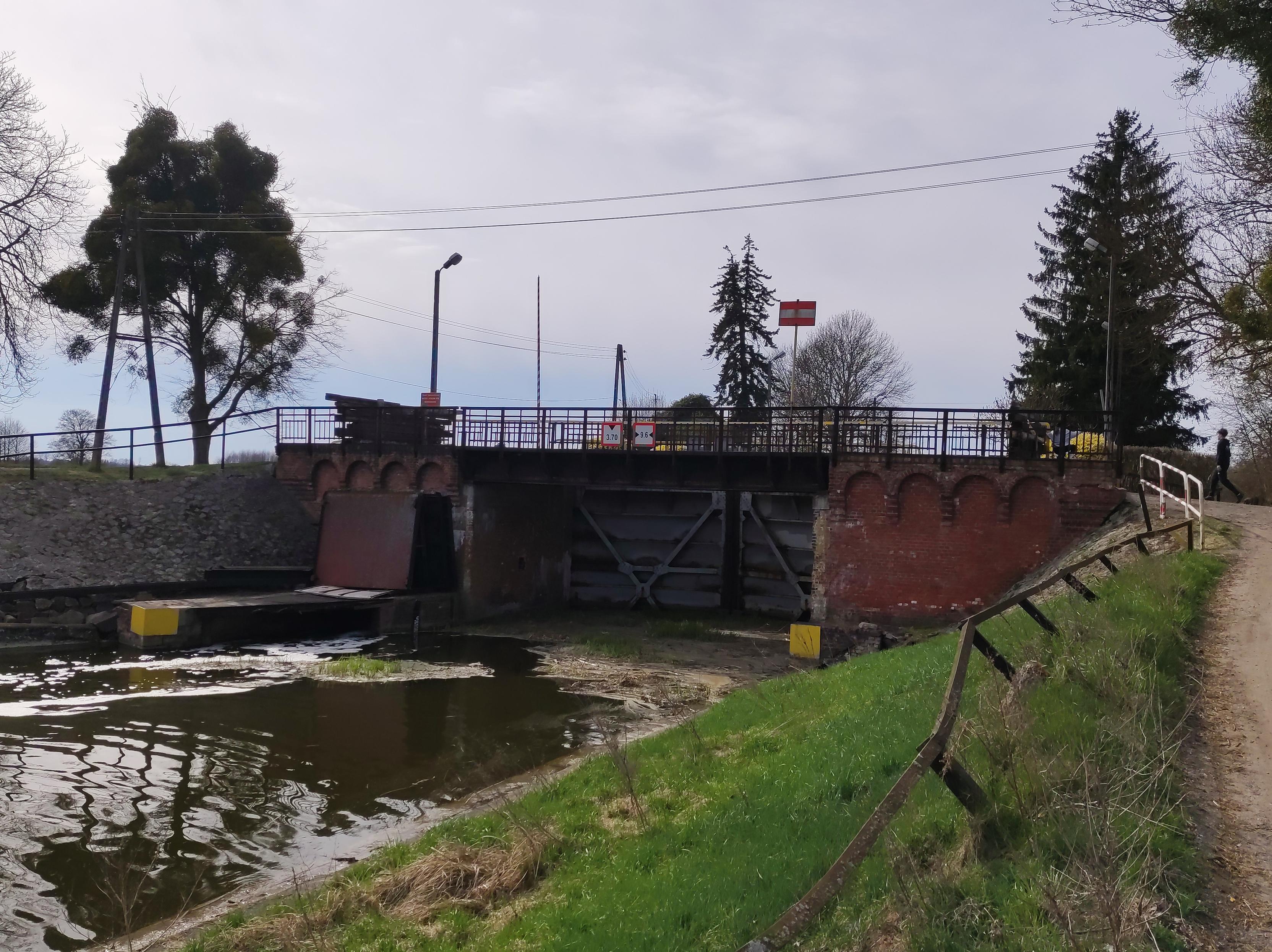 Ceglana śluza o metalowych wrotach na kanale.