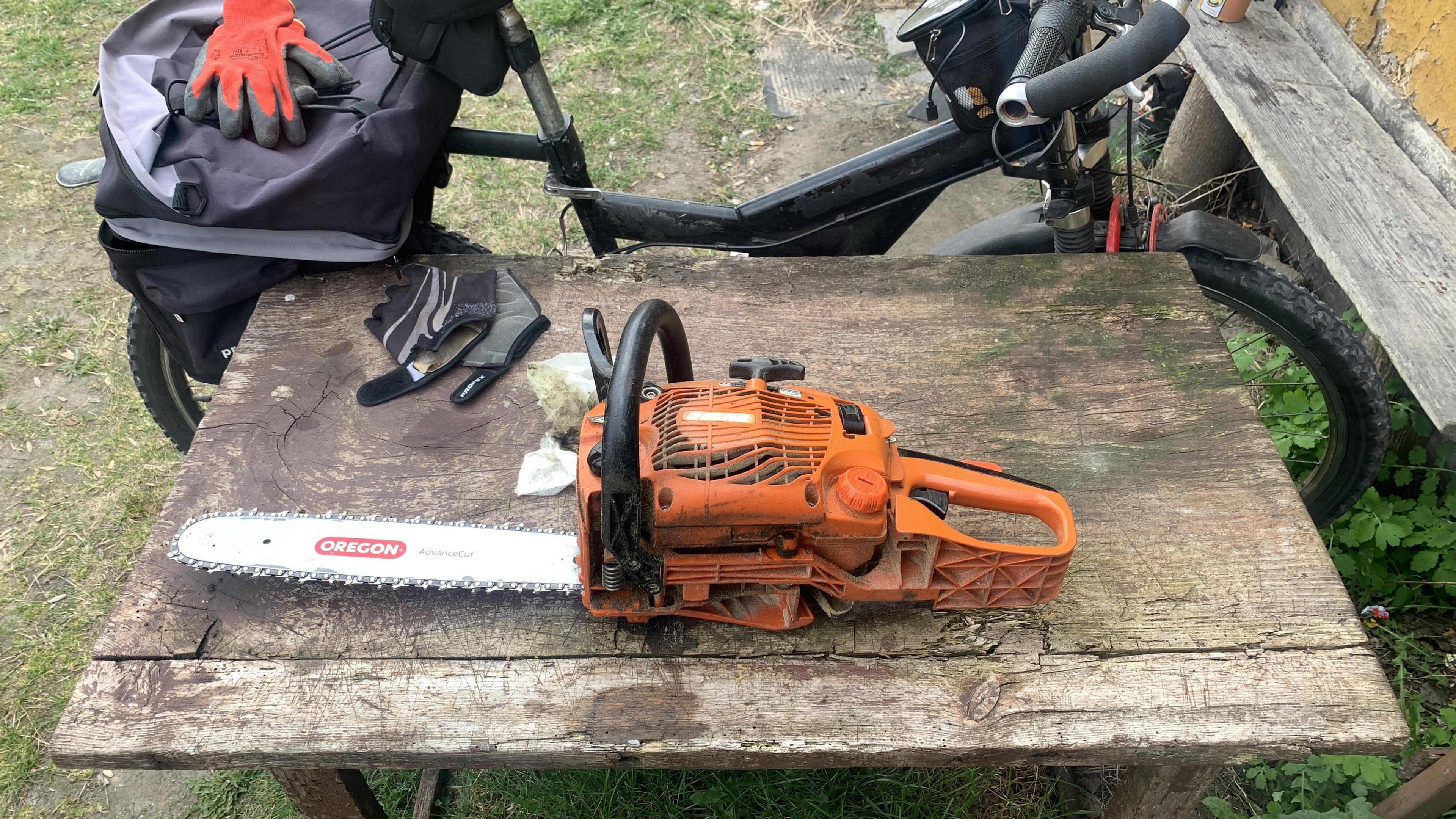 Japońska piła łańcuchowa Echo na starym stole z topoli. W tle rower terenowy