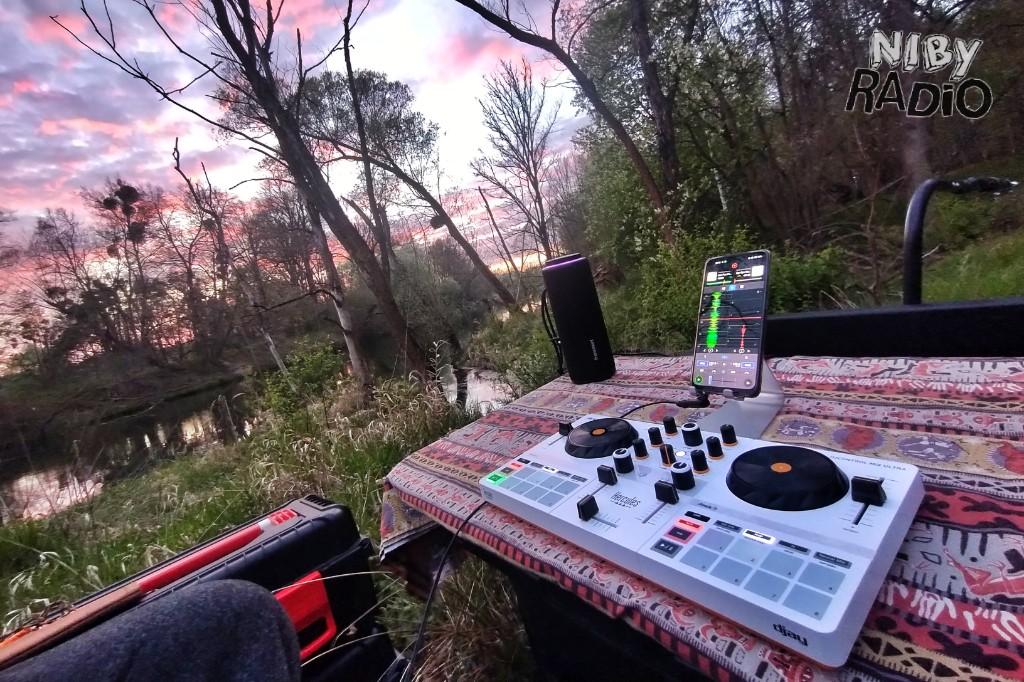 Terenowy zestaw Niby DJ-a nad rzeką o zachodzie słońca.