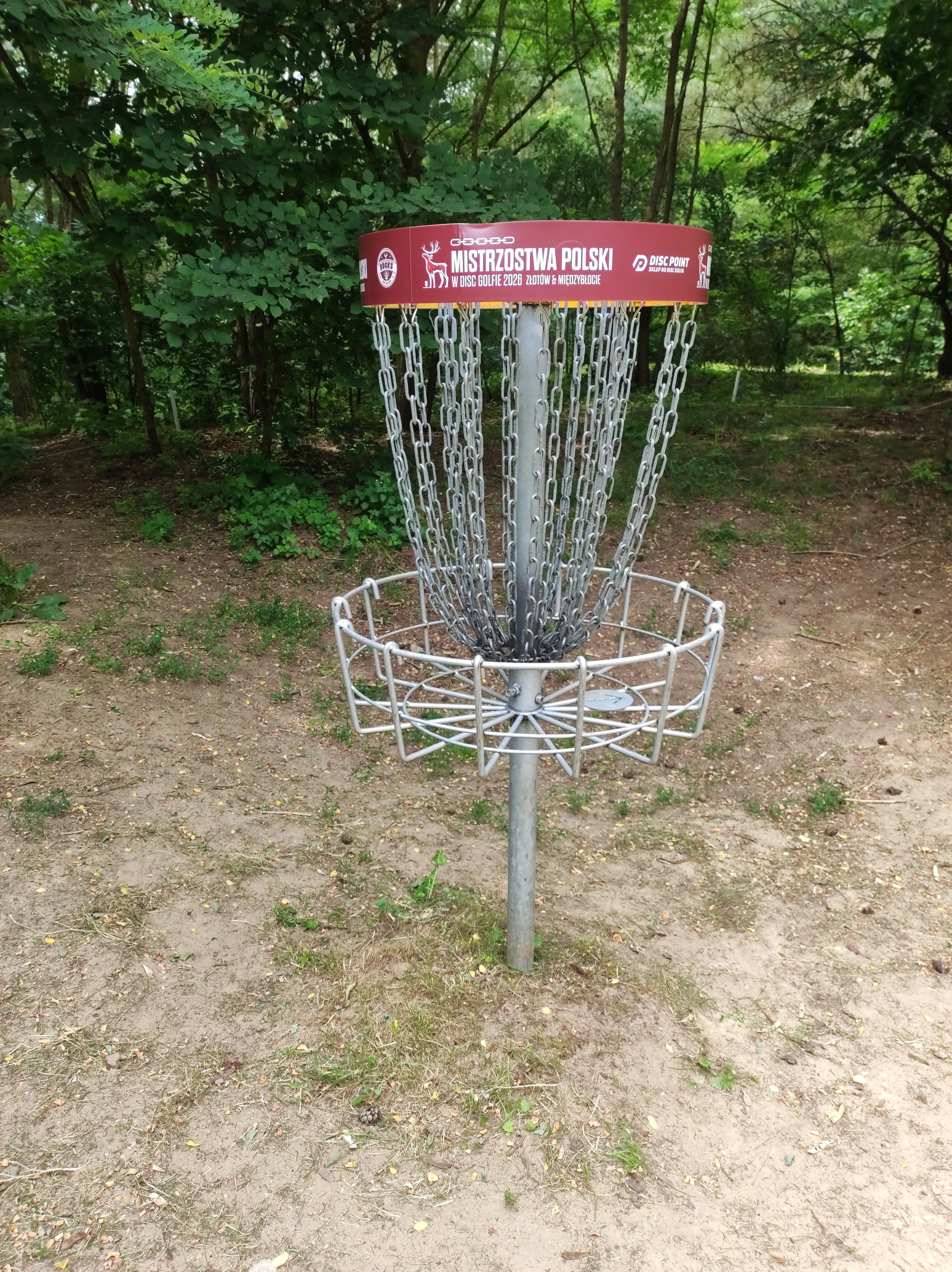 Kosz do disc golfa na którego obręczy jest napis Mistrzostwa Polski w disc golfie 2026 Złotów i Międzybłocie.