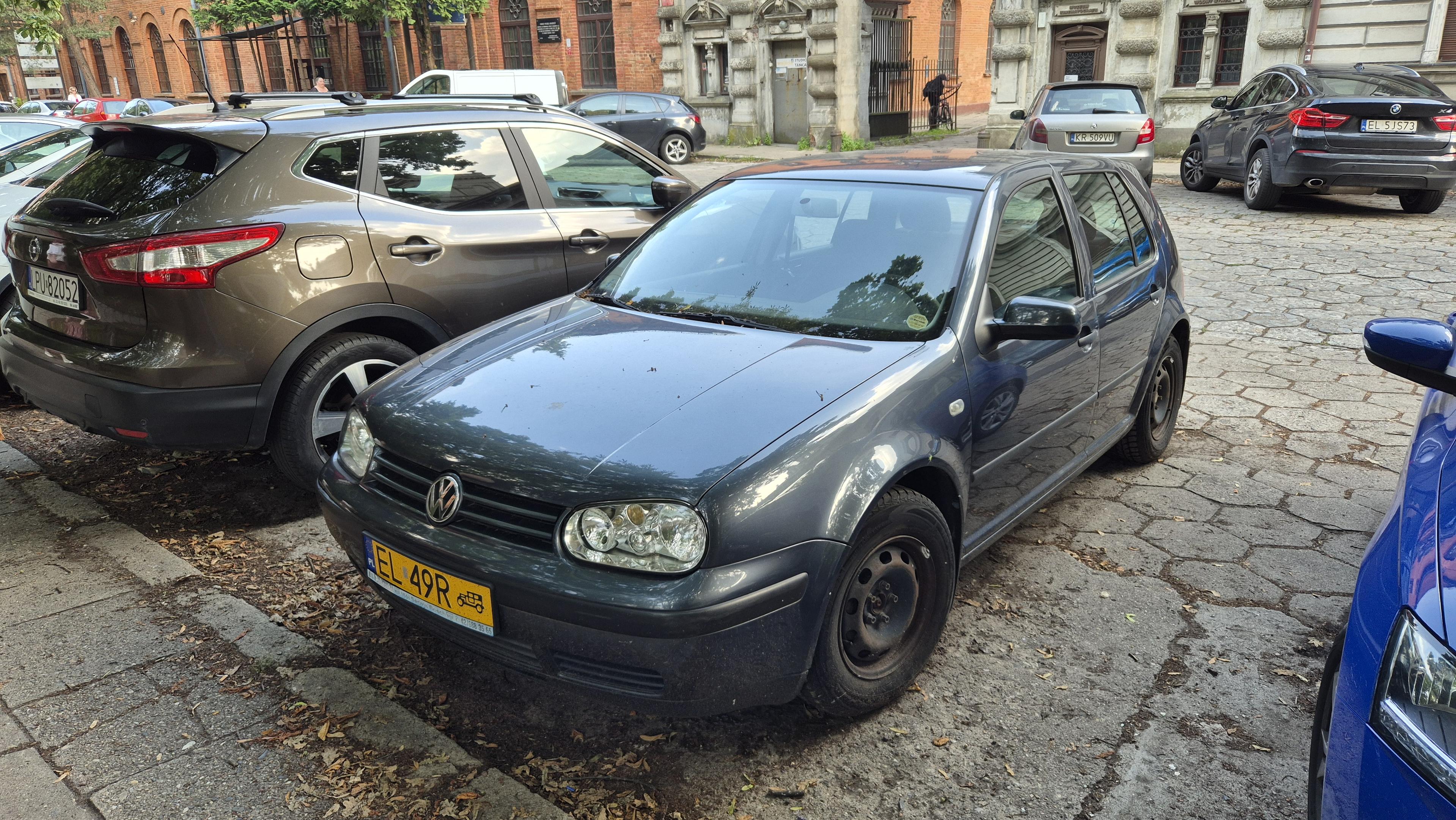 Zużyty Volkswagen Golf 1,9 TDI na parkingu, zarejestrowany na żółte tablice dla pojazdów zabytkowych.