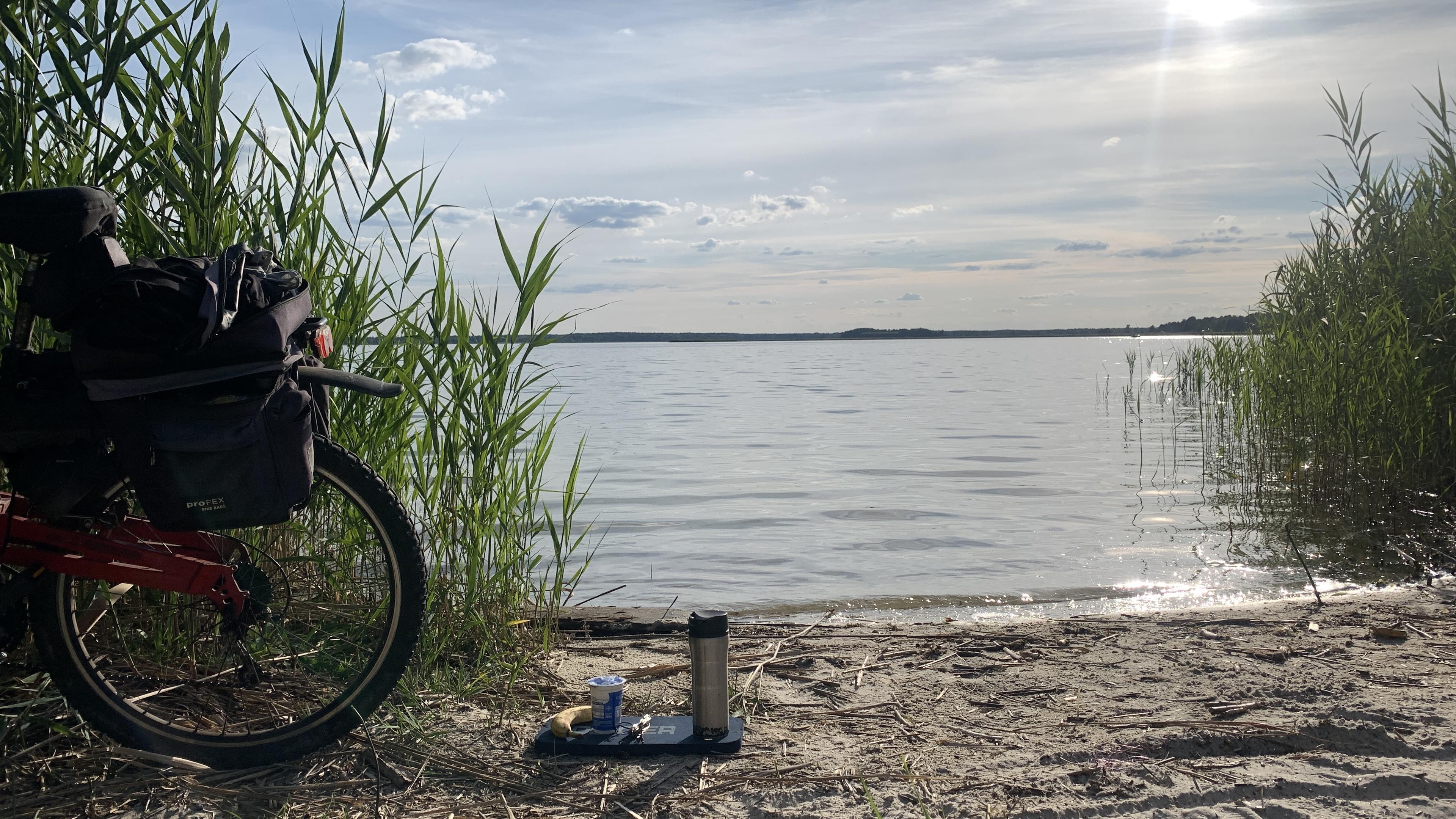 Piaszczystya plaża nad jeziorem, tatarak, słonecznie. Kawa, jogurt i banan