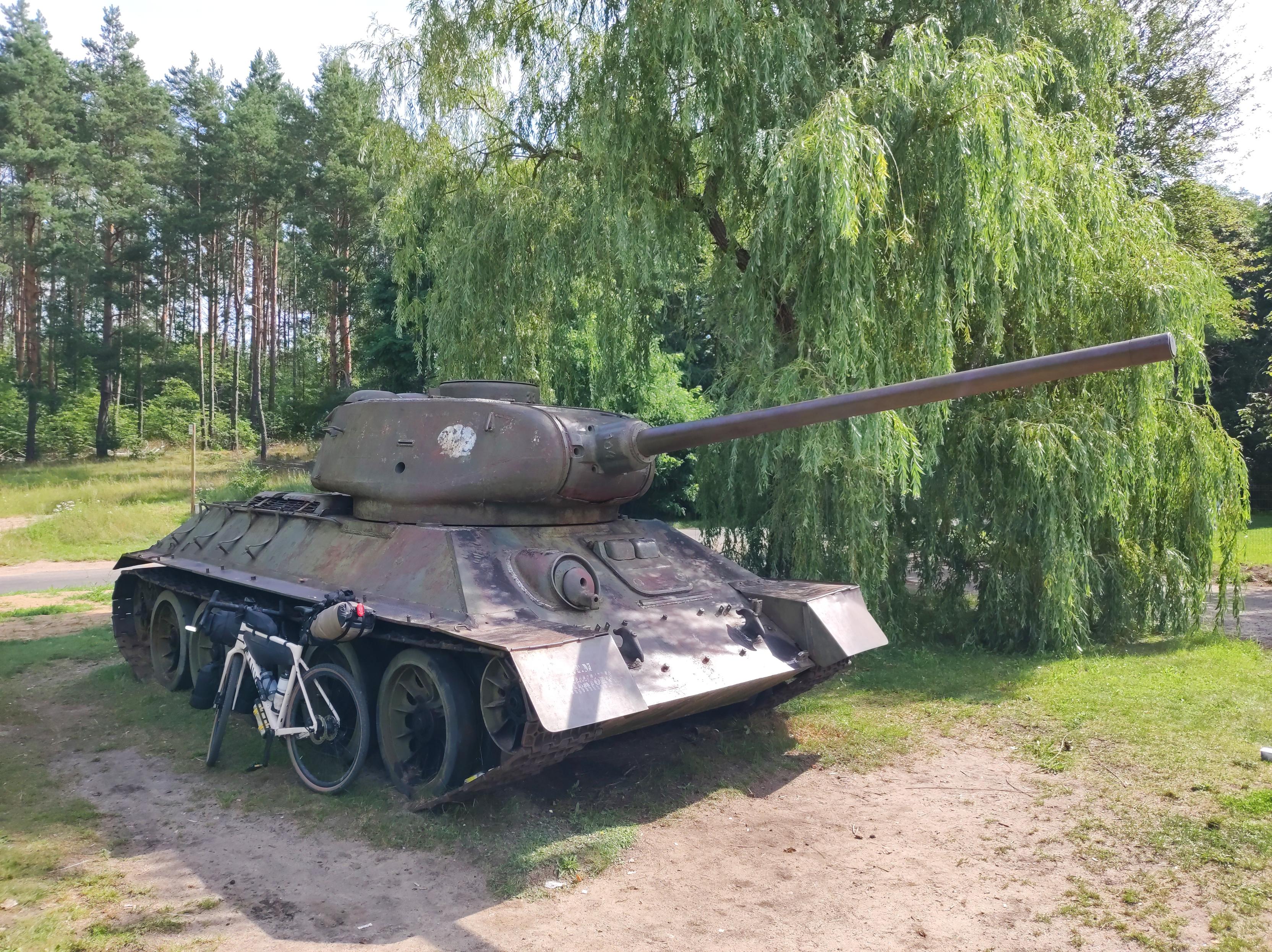 Czołg T-34/85 i oparty o gąsienicę rower szutrowy z bikepackingowymi torbami.